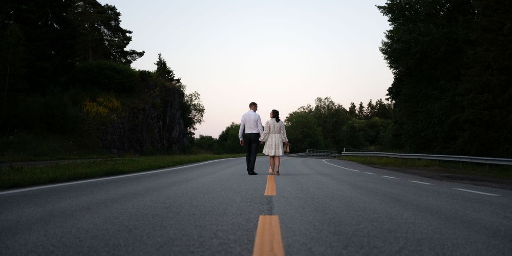 Person walking on a winding rural road at sunset with yellow median lines visible.