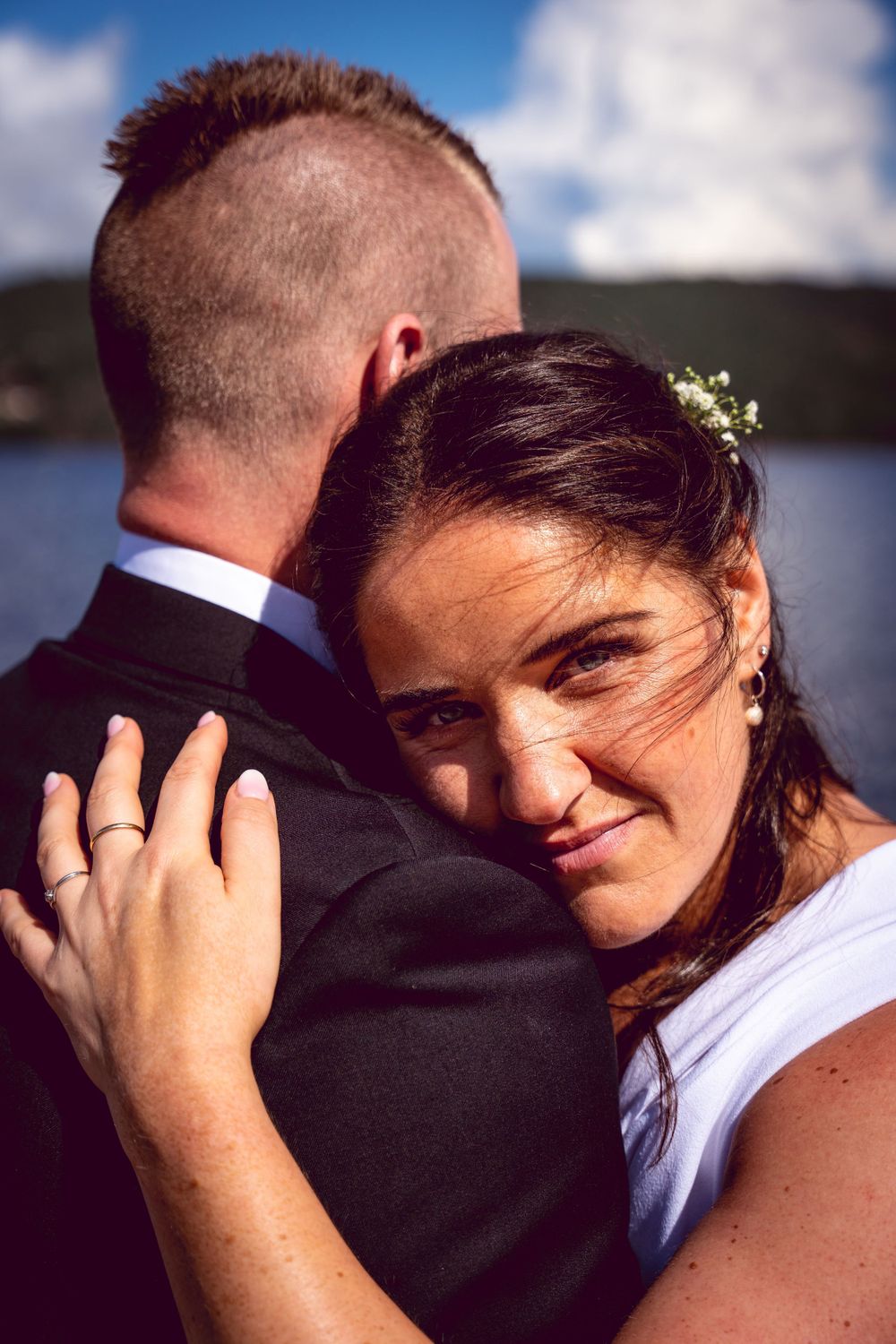 Romantic wedding portrait captured against mountain lake backdrop.