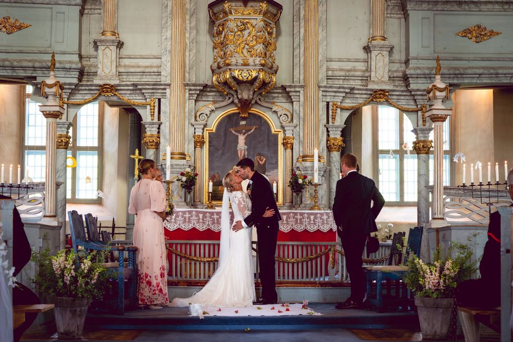 Traditional church wedding ceremony in ornate historic altar setting with decorative gold details.