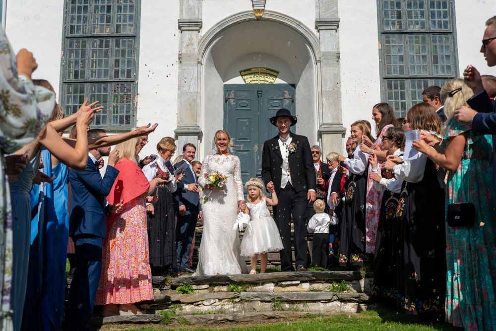Wedding exit celebration with guests throwing petals outside historic white church.