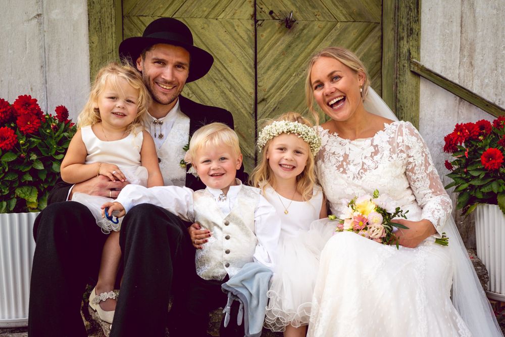 Wedding celebration on rustic porch with red flowers and greenery.
