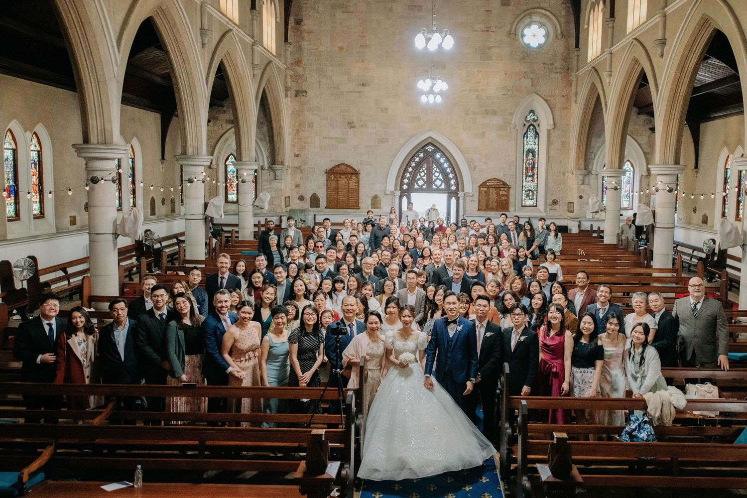 Wide view of wedding congregation gathered in a grand cathedral with gothic arches.