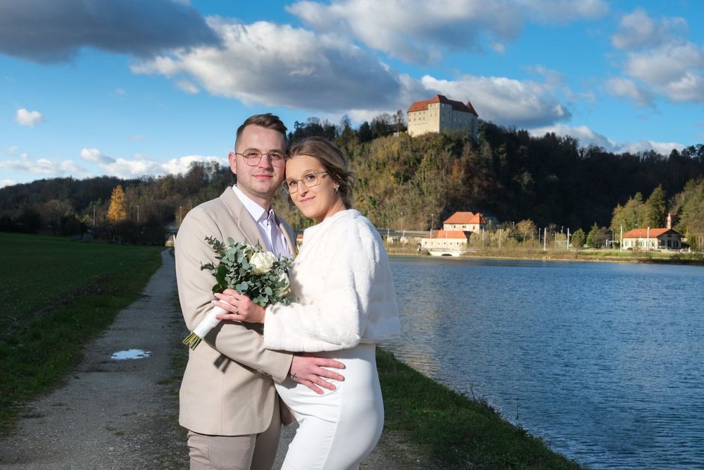 Poročni par ob reki Savi z gradom Rajhenburgom v ozadju v Posavju – profesionalno fotografiranje poroke Krško.