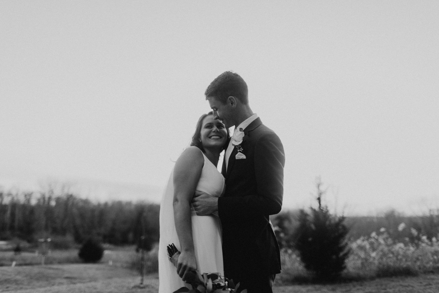 A black and white intimate moment captured between a couple in wedding attire.
