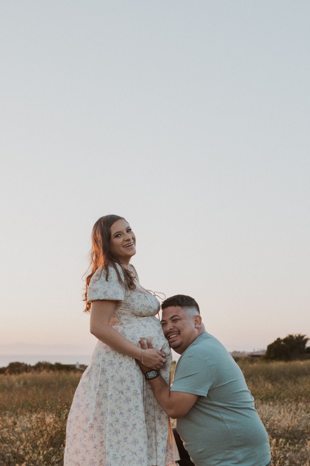 A tender maternity moment captured in golden evening light.