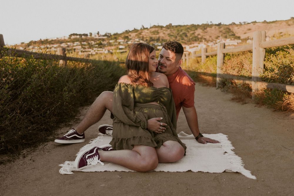 A couple sits on a white blanket on a path during golden hour.