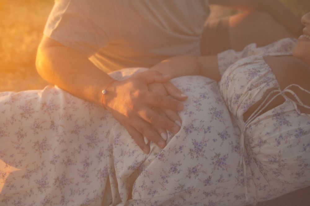 Gentle hands rest on floral fabric during sunset.