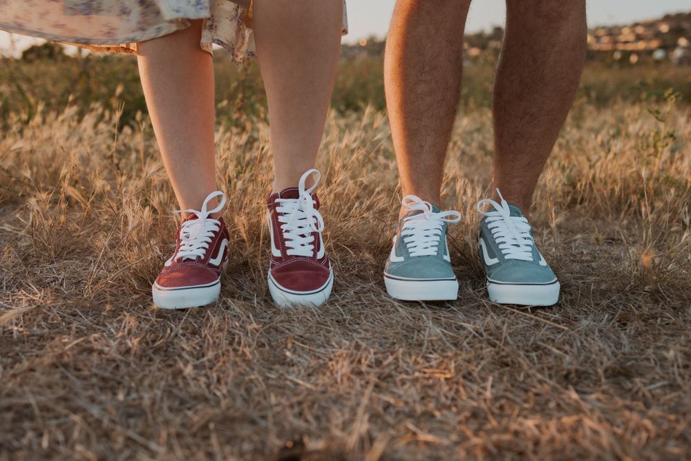 Two pairs of sneakers shown side by side on dry grass.