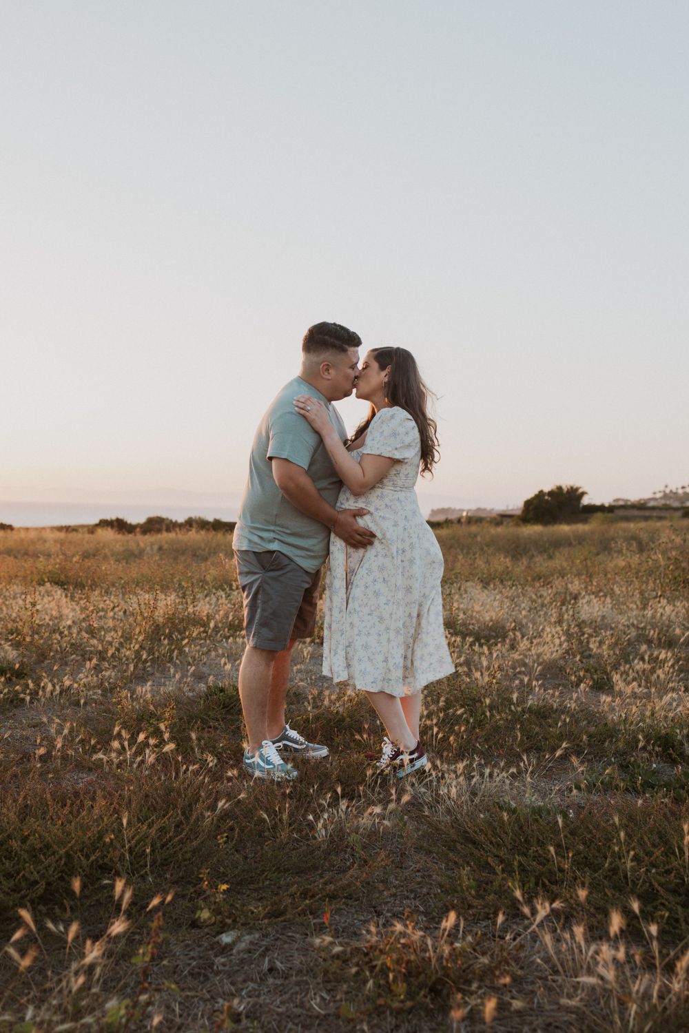 A romantic moment shared between a couple in a field at dusk.