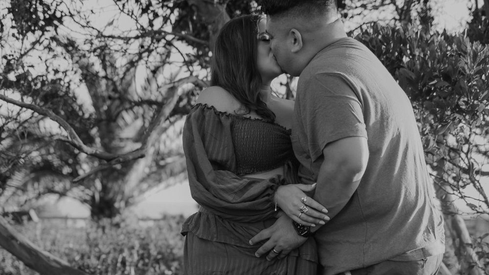 Intimate black and white photo of a couple embracing in an outdoor setting.