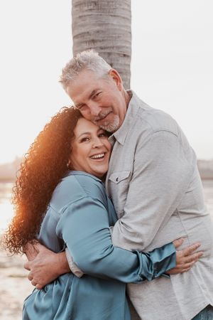Intimate embrace between two people during sunset by the beach.