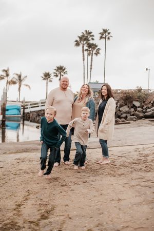 A family enjoys a casual beach day together near palm trees.