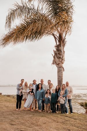 Group portrait under a palm tree by the ocean at golden hour.