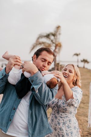 Couple playing and laughing together outdoors in casual attire.