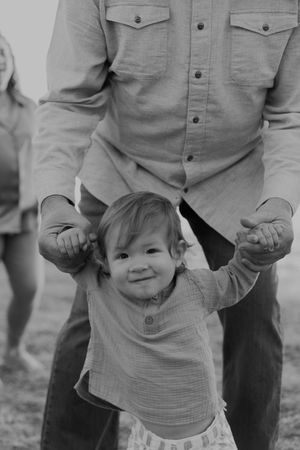 Candid black and white photo of a child smiling while holding hands.