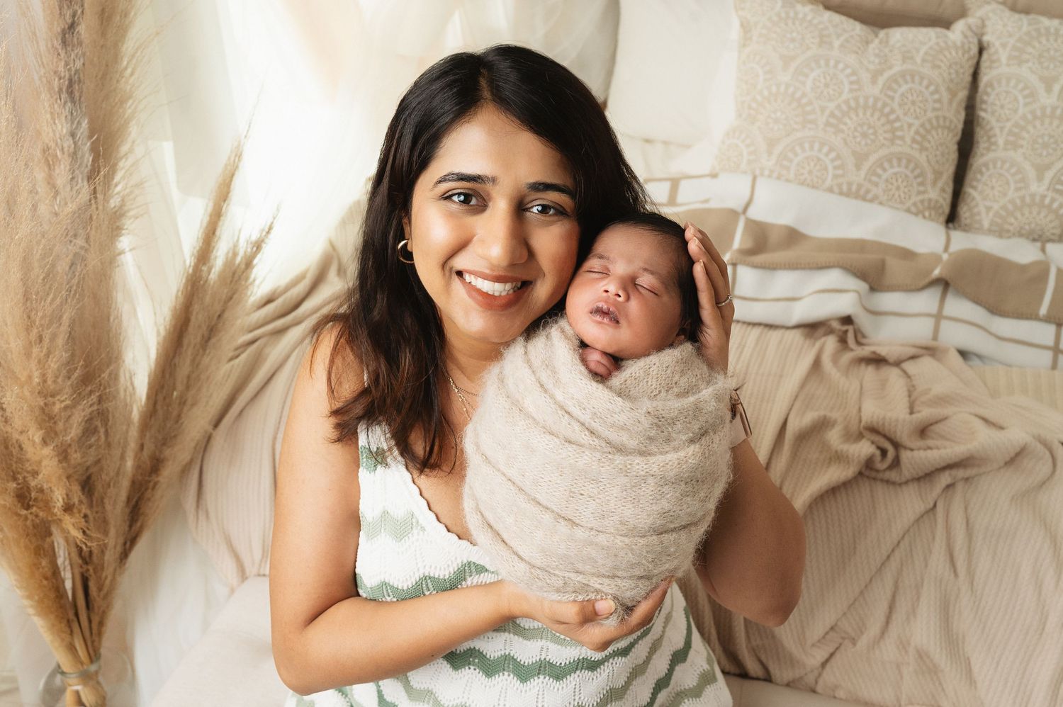 Parents sharing tender moment with newborn on white bedding during lifestyle photography session.