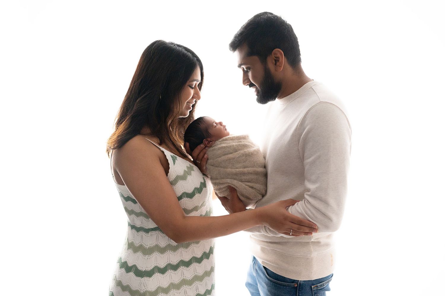 Family portrait with parents in casual wear holding their newborn.