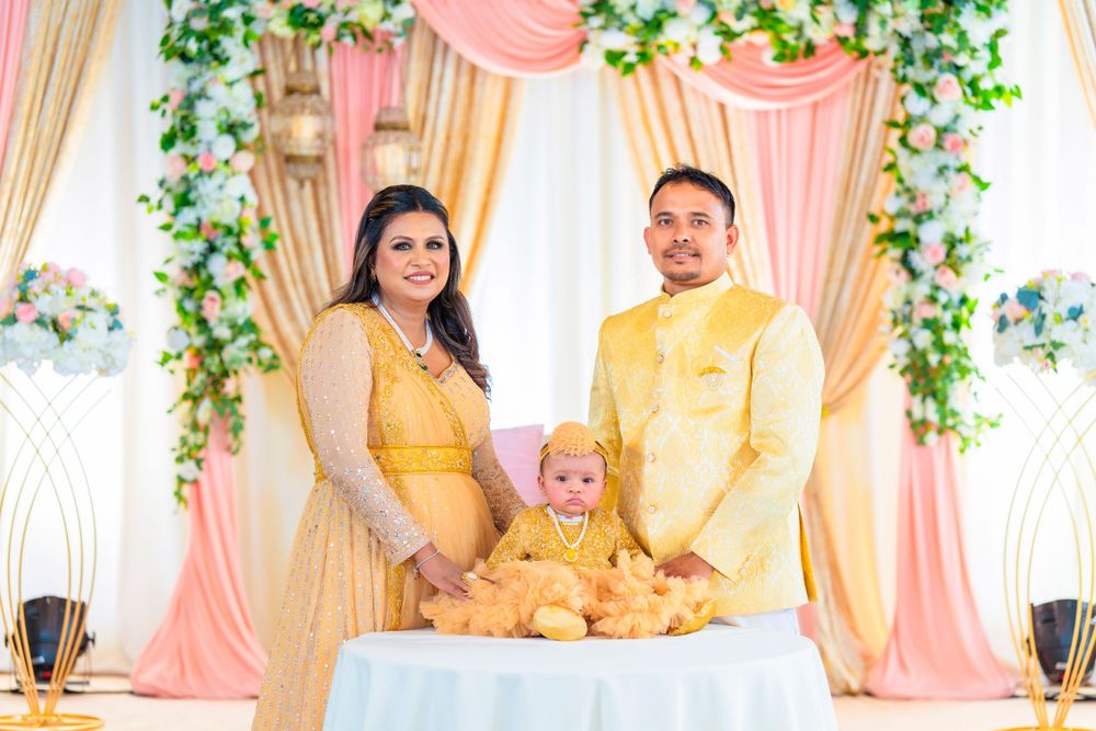 Family in coordinated yellow outfits poses together at decorated event backdrop.