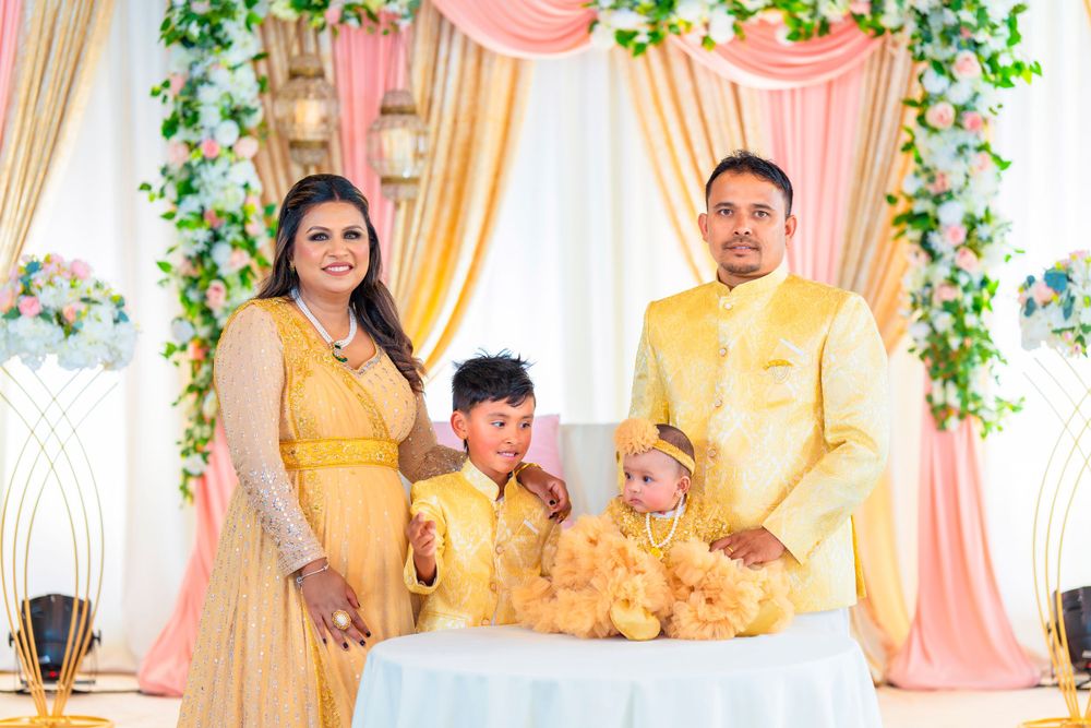 Family of four in matching yellow attire poses at decorated event backdrop.