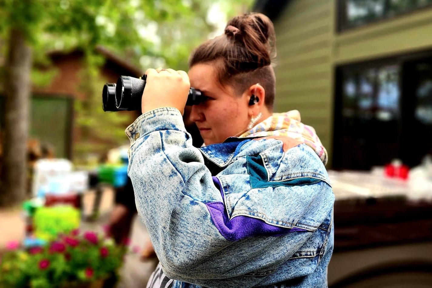Photographer capturing images with a camera while wearing a denim jacket.