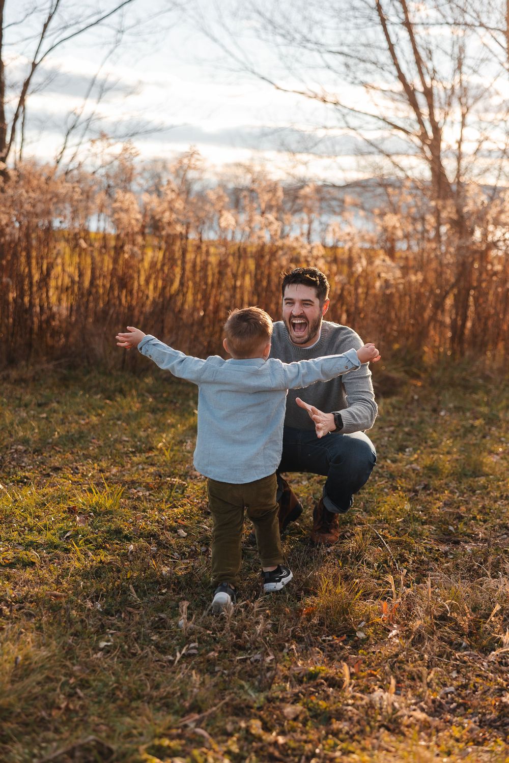 Two people playing and laughing together in a golden autumn field at sunset.