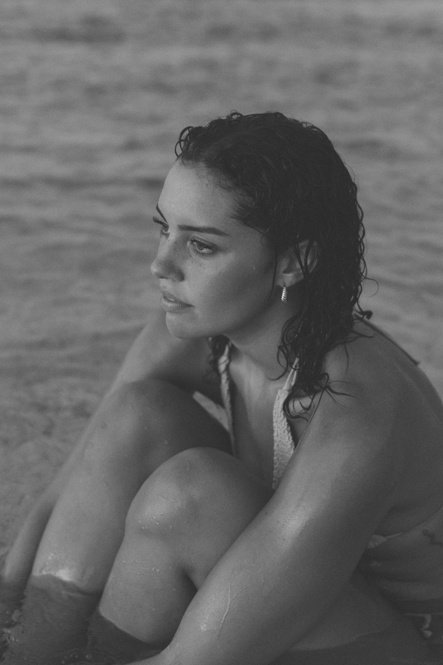 Moody black and white portrait of a person with wet hair by the water.