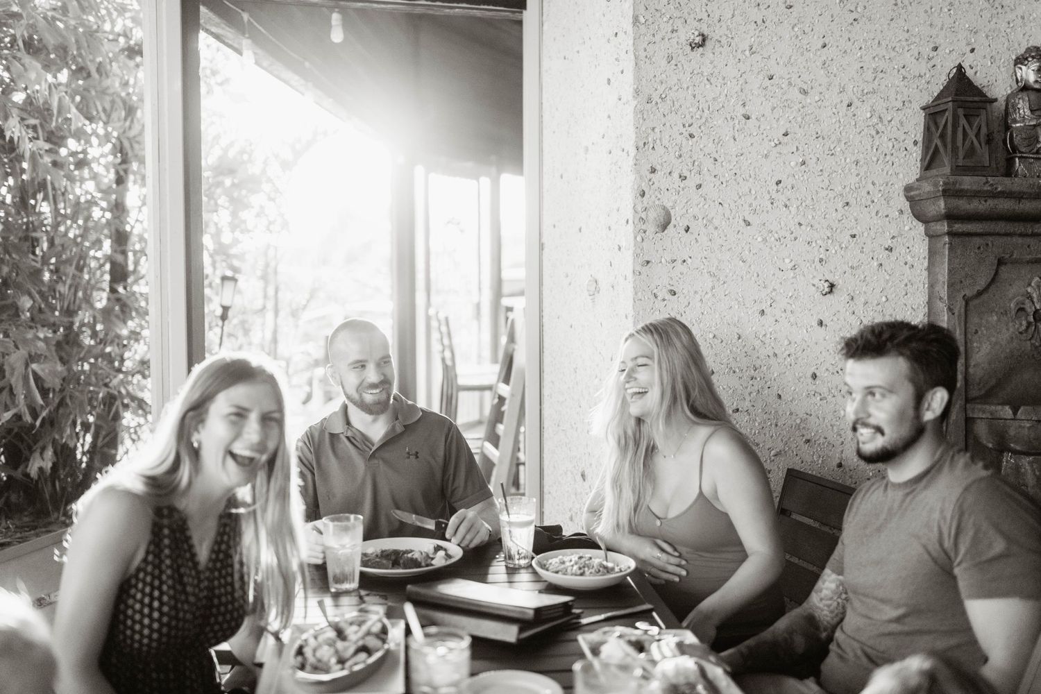 Friends enjoying a casual meal together at an outdoor restaurant in black and white.