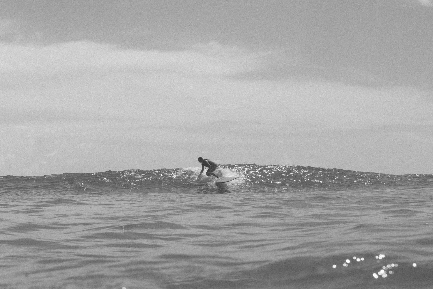 Distant view of a surfer catching a wave on the open ocean.