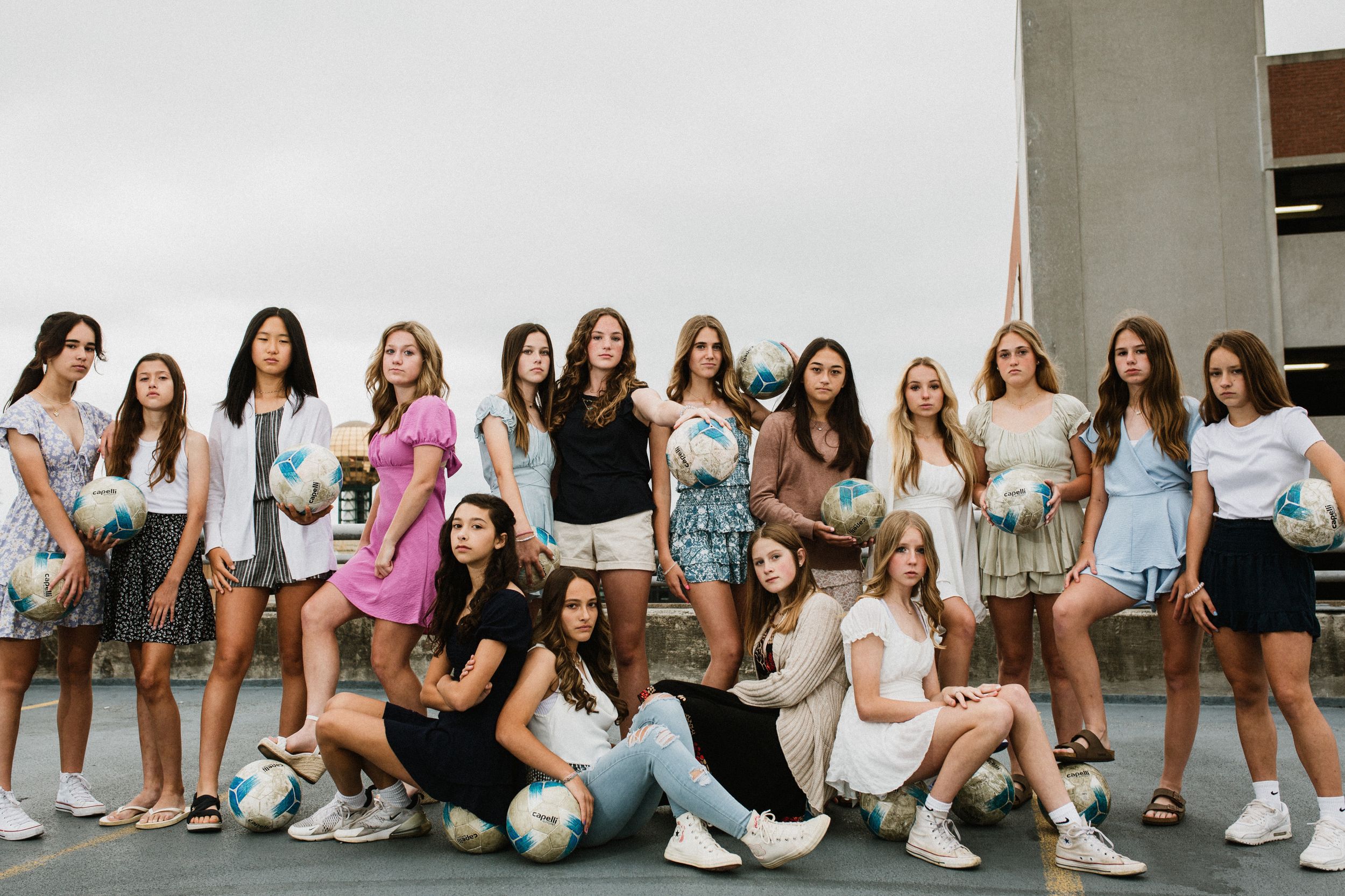 Group photo of young women posing outdoors against concrete wall.