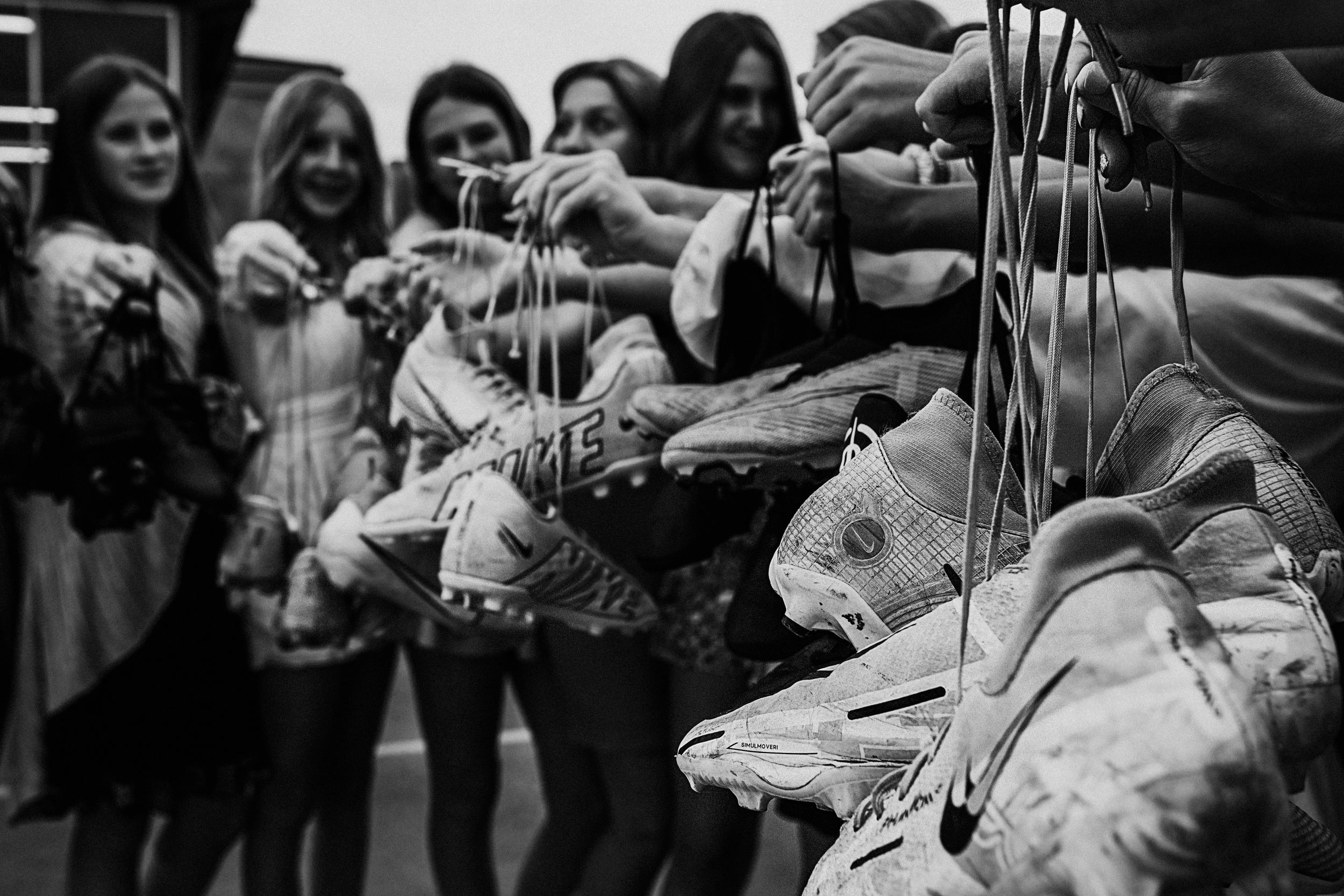 Black and white image of hands reaching for pointe ballet shoes.