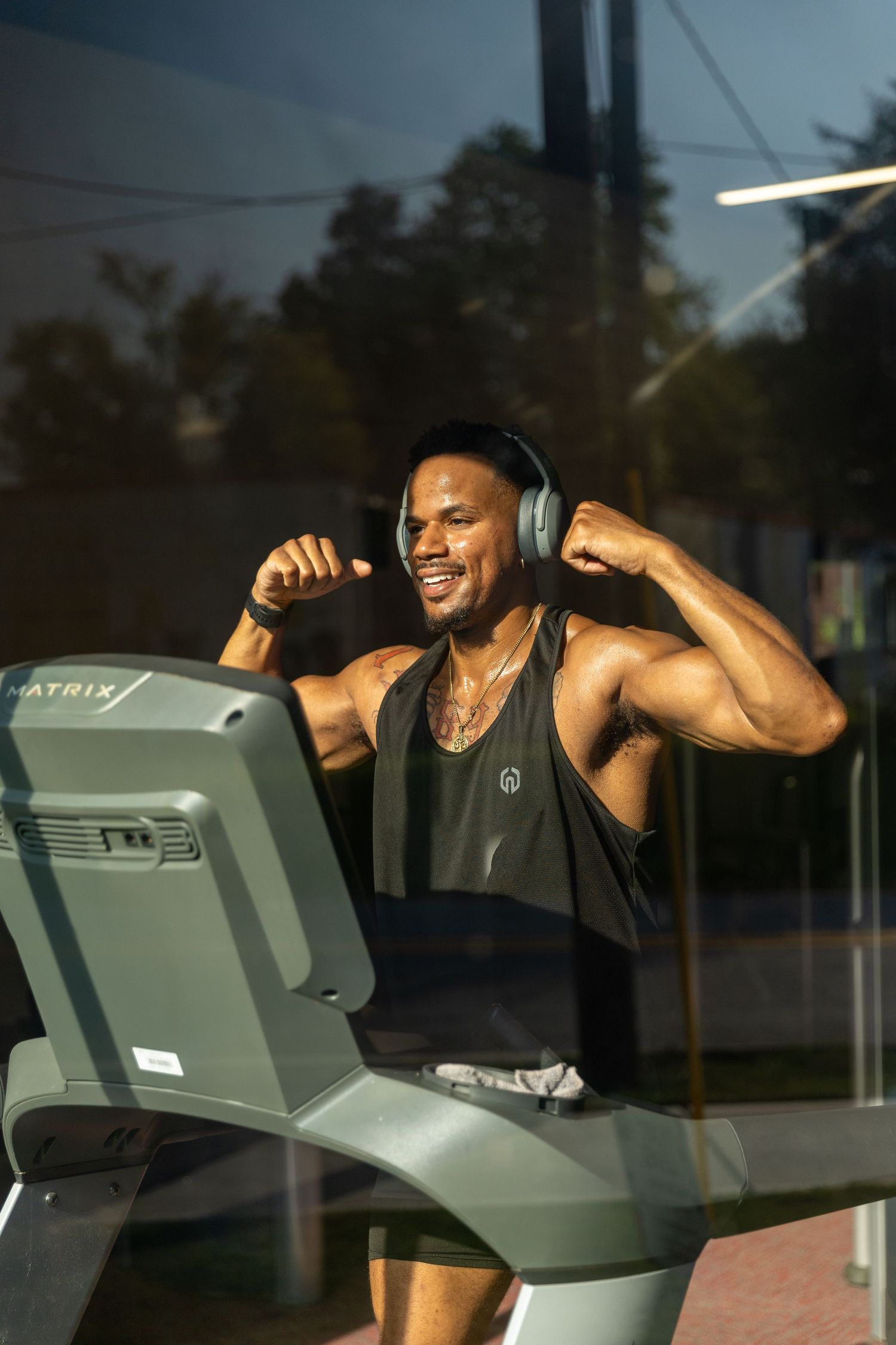 Athletic person working out on treadmill while wearing headphones and smiling with enthusiasm. | Shot By Lo™