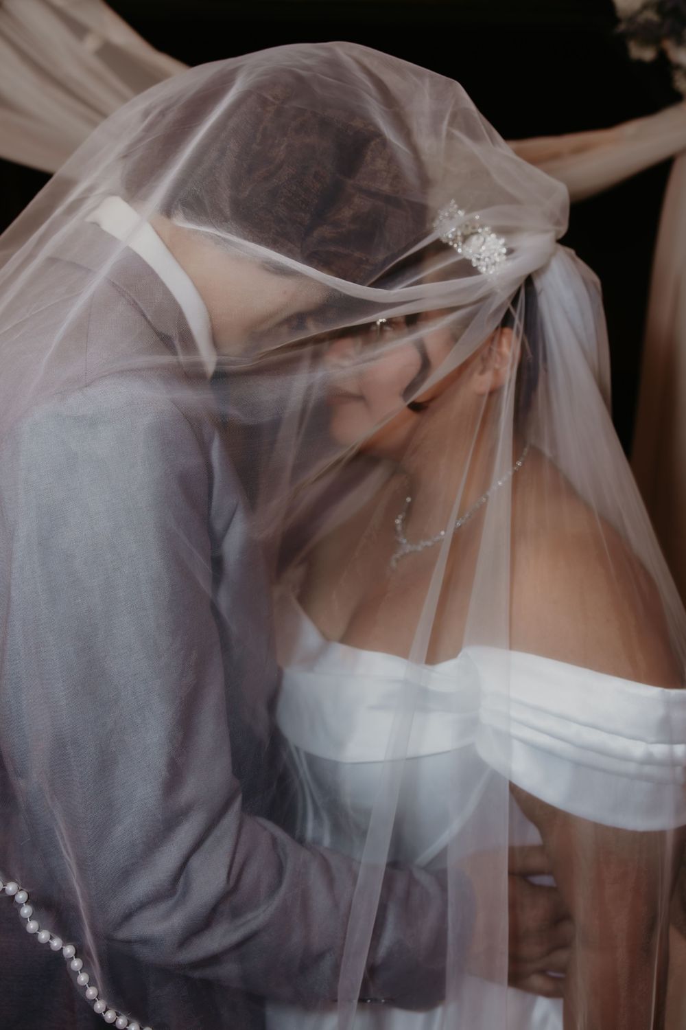A romantic wedding moment captured through delicate white veil during an intimate ceremony.