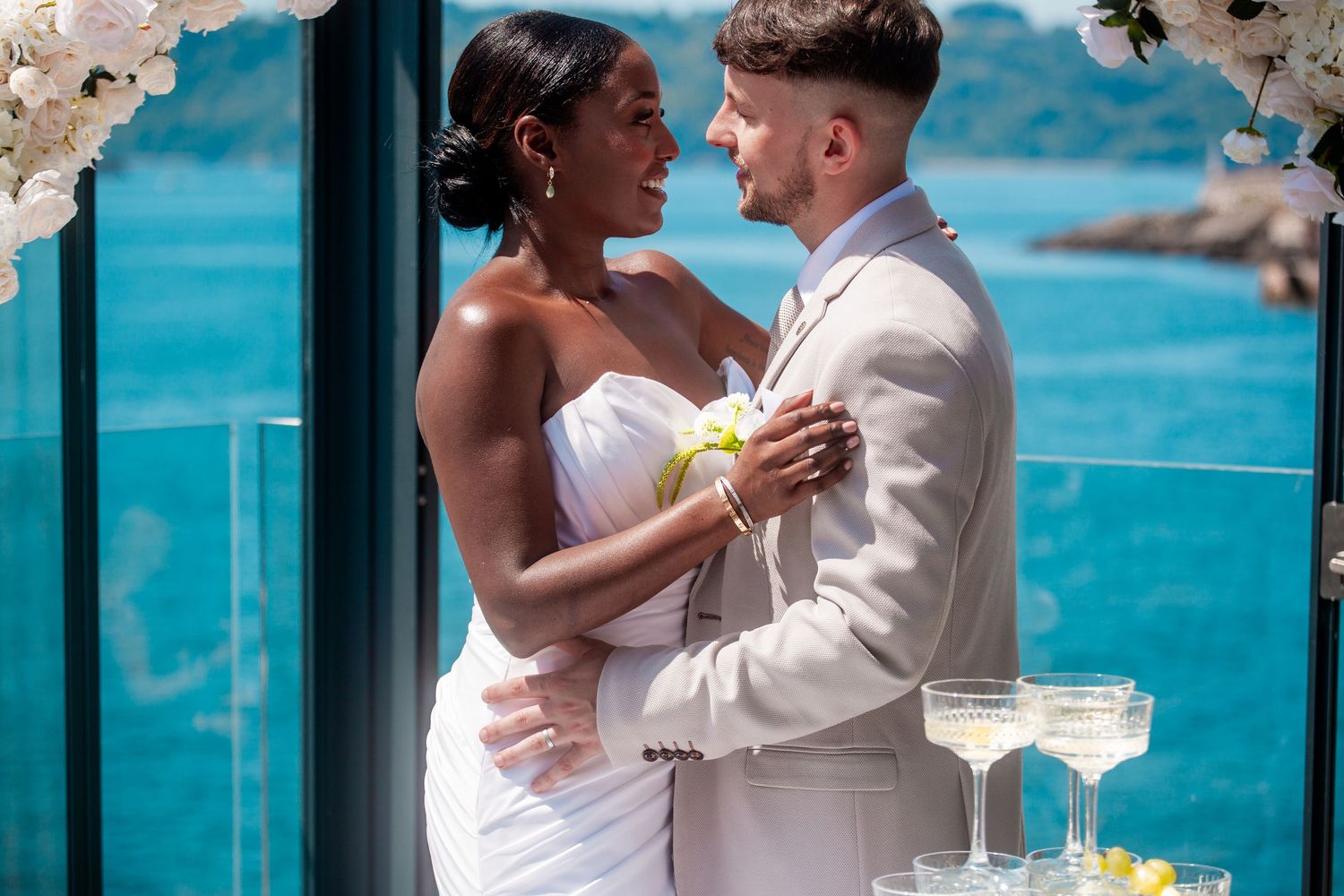 Romantic beachside wedding portraits with turquoise ocean and cherry blossoms in the background.