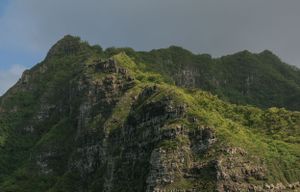 Lush green mountain ridge in Hawaii with dramatic cliffs and slopes.