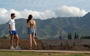 Couple admiring scenic mountain views from hilltop overlook.