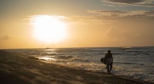 Golden sunset over ocean horizon with silhouetted coastline.