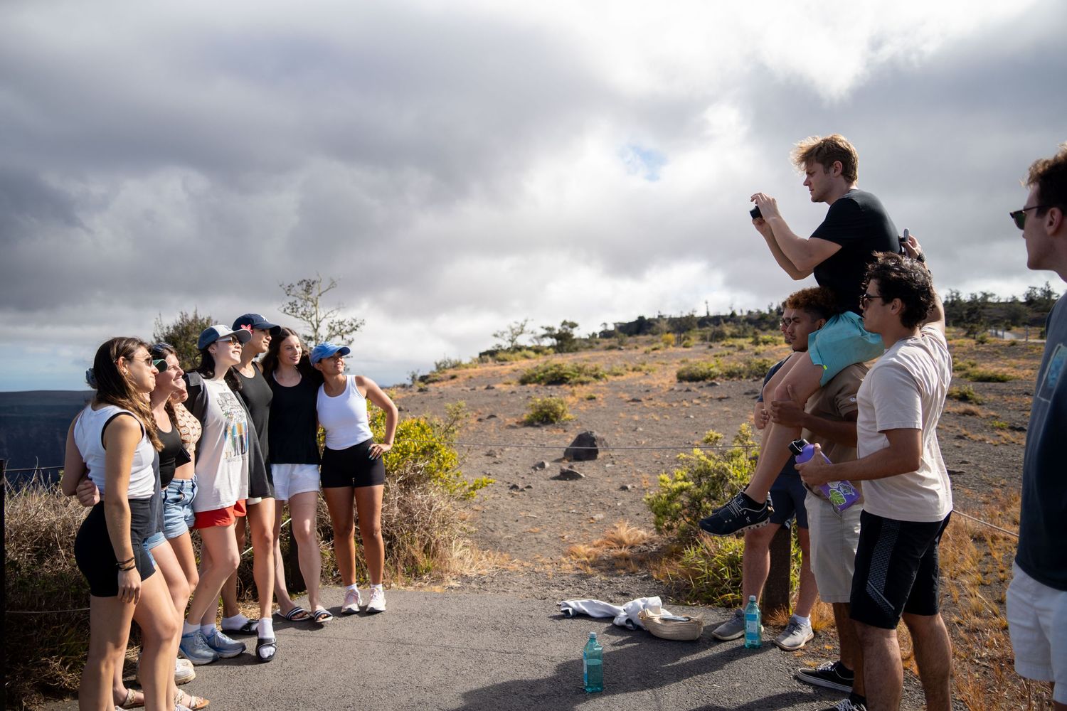 Group of people gathered on a coastal hiking trail overlooking the ocean.