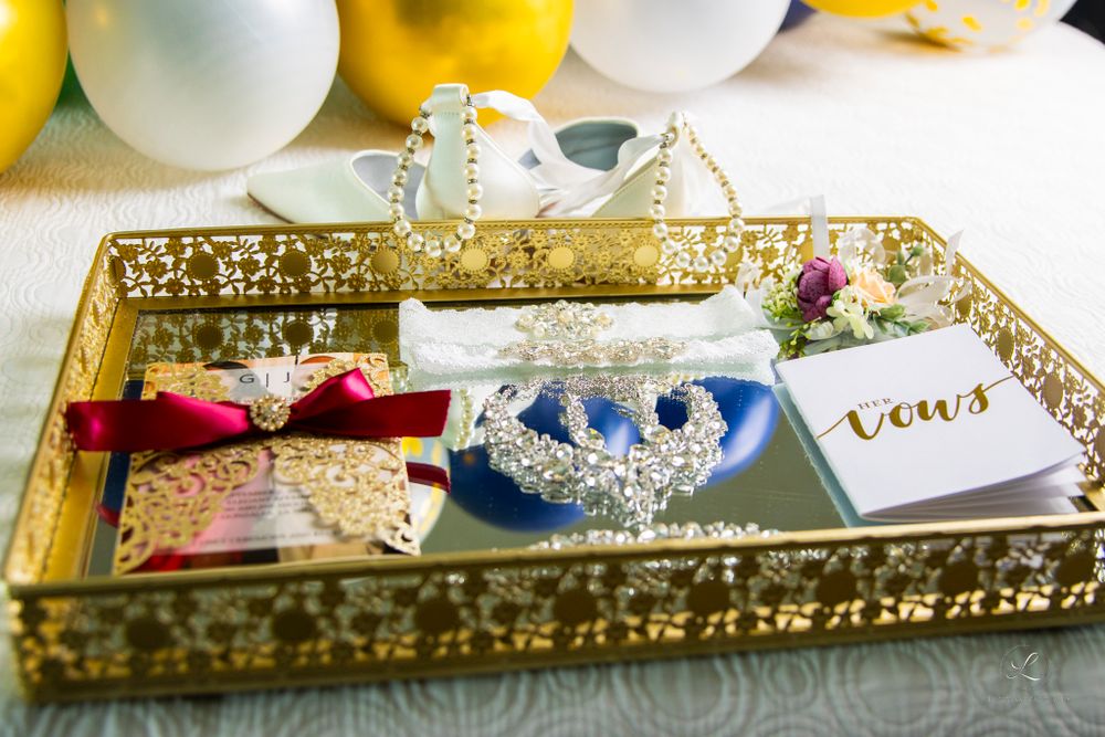 Wedding accessories and decor displayed on an ornate gold tray including crowns and handwritten cards.