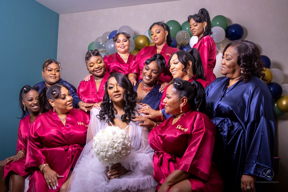Wedding party in pink and navy robes posed with balloons and celebratory expressions.