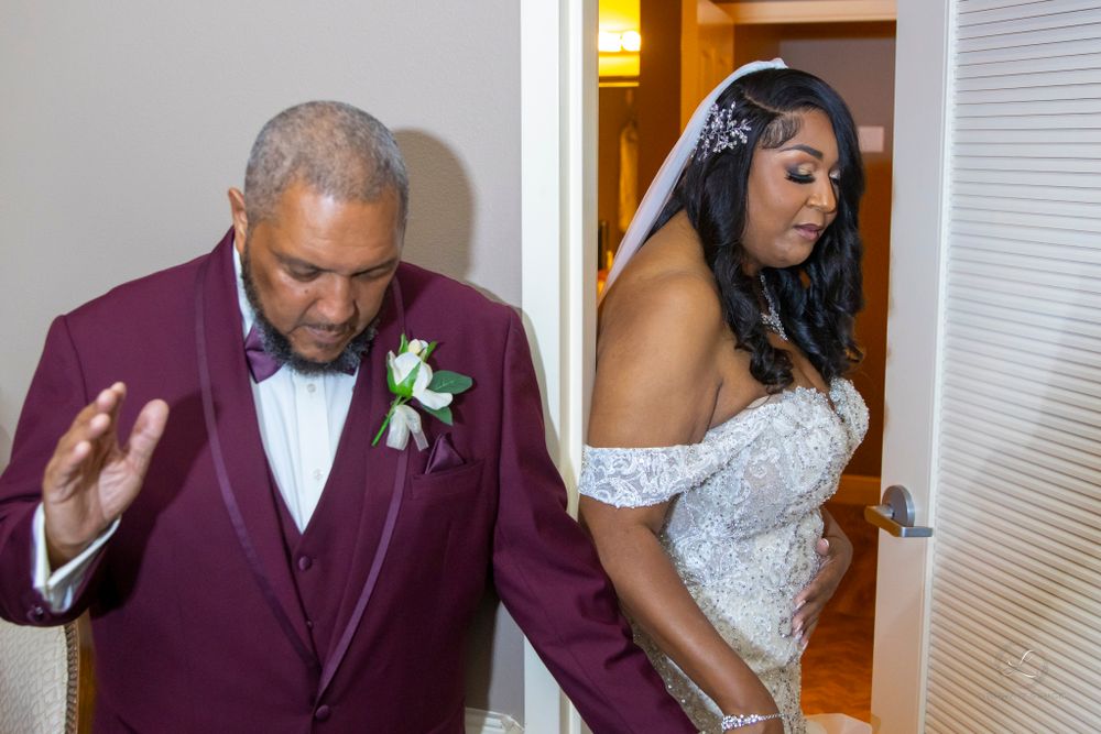 Wedding party celebrating in a hallway wearing elegant suits and white dresses.