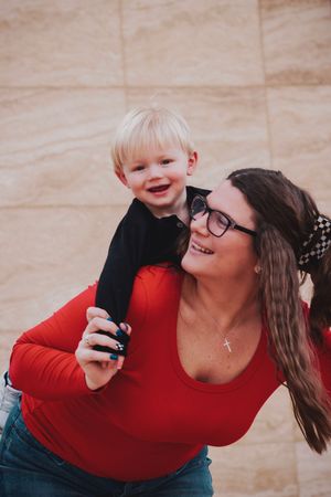 A joyful sequence of candid moments between a parent and child in matching red against a beige backdrop.