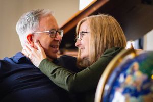 Two people embrace warmly in a candid moment during what appears to be a casual indoor gathering.