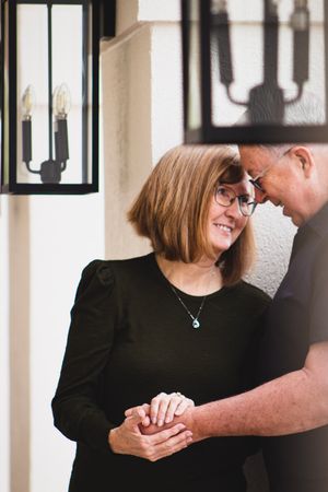 A couple shares an intimate moment laughing together on a porch with lantern lighting in the background.