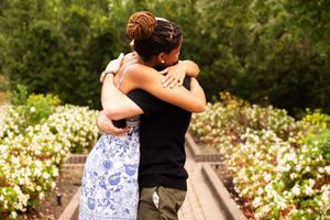 Two people dancing together in a garden setting surrounded by white flowers and greenery.