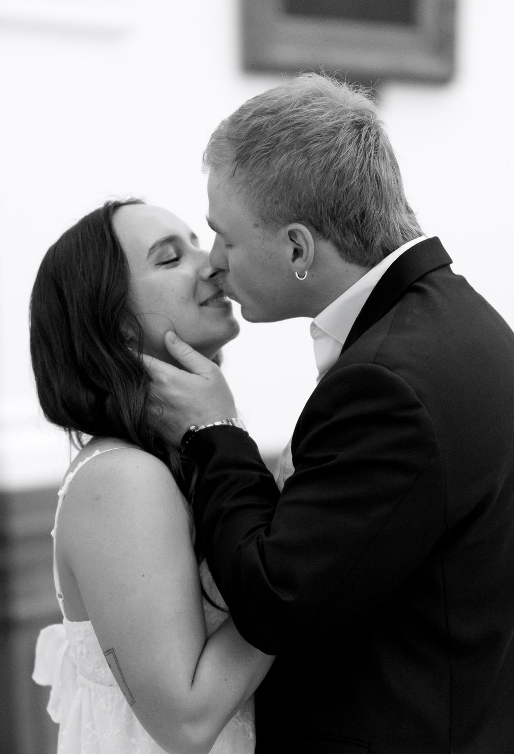 A black and white intimate portrait of a couple sharing a romantic kiss.