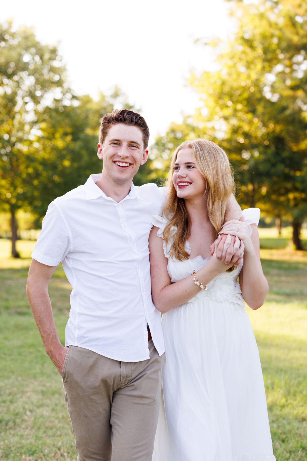 Happy couple laughs together during outdoor photo session in park.