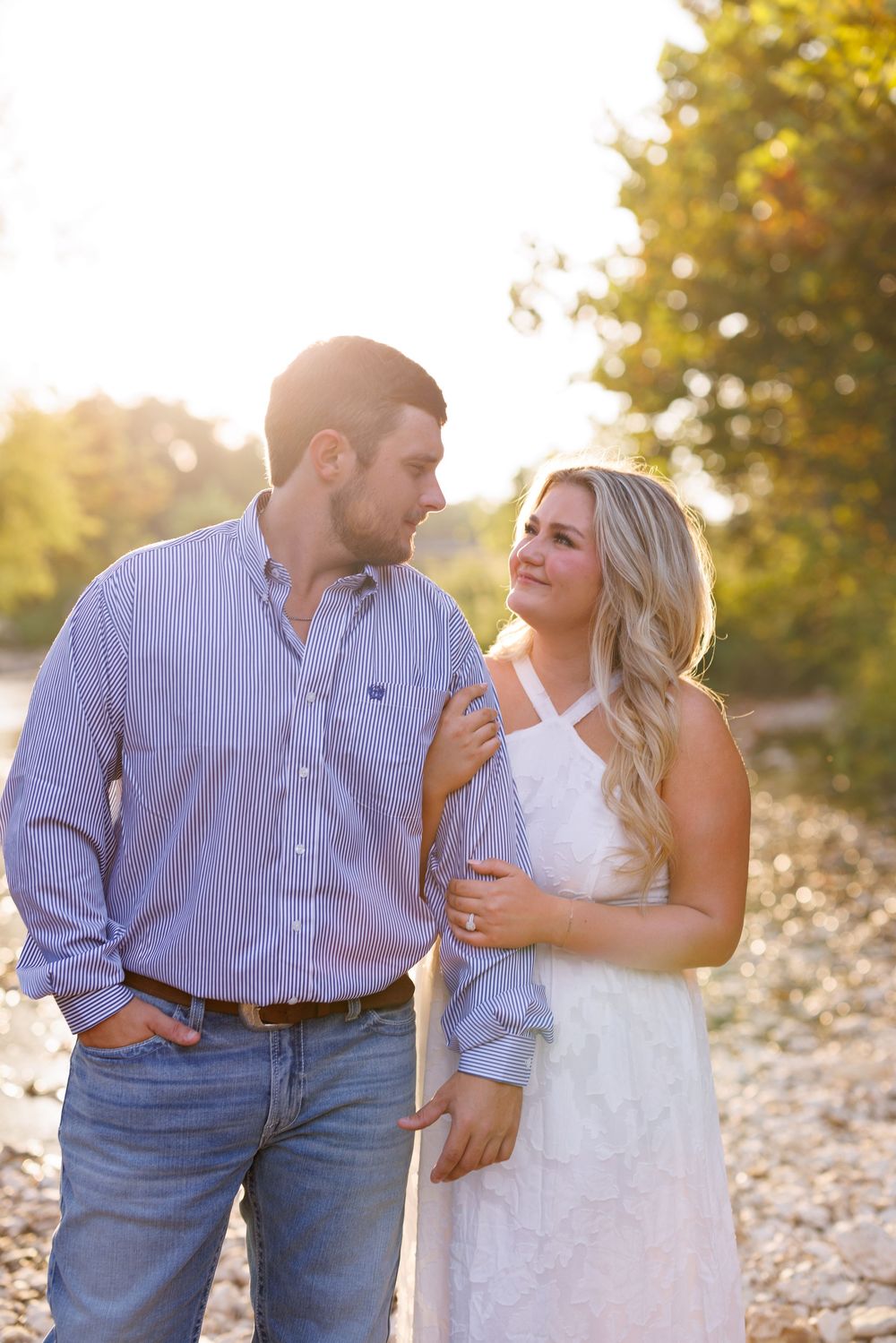 A romantic couple shares intimate moments during their engagement photoshoot in a natural outdoor setting.