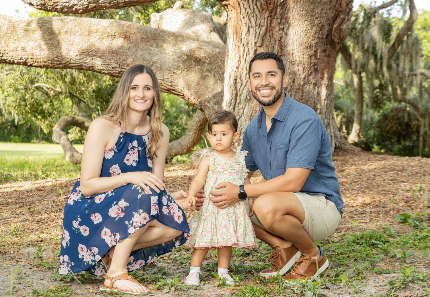 A family wearing blue and white outfits poses together for outdoor portrait photos in a natural park setting.
