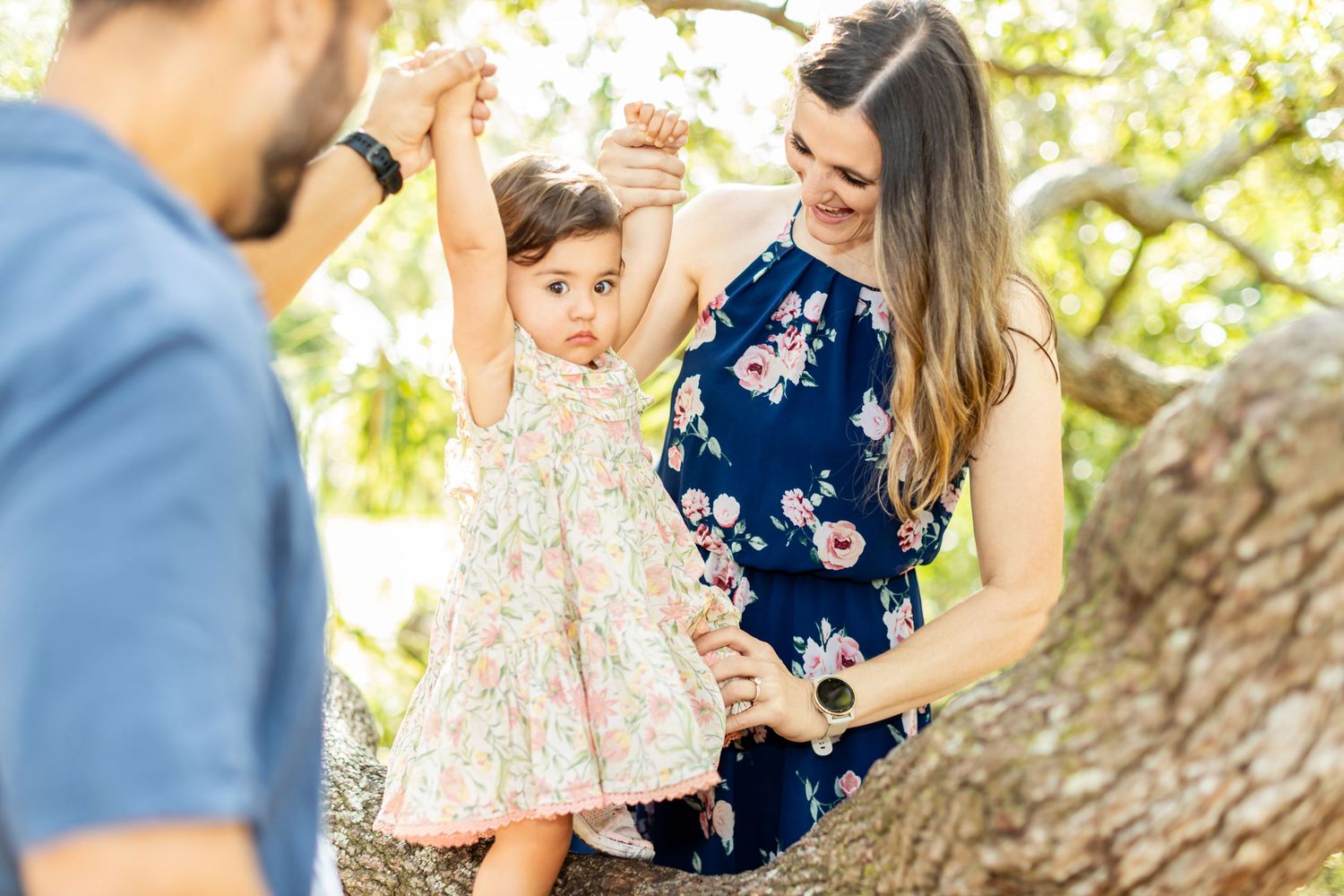 A candid outdoor family portrait capturing joyful moments in a sunlit natural setting during spring time.
