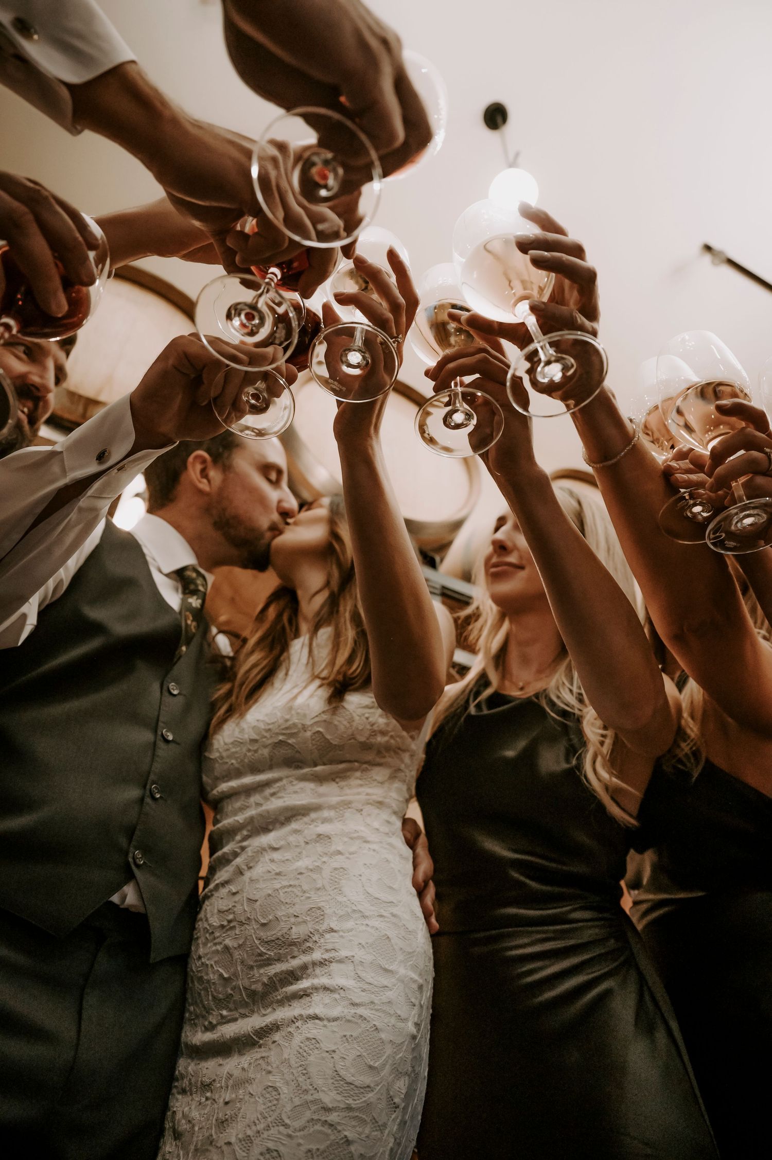 A wedding celebration captured from below as guests raise champagne glasses in a joyful toast at a winery in the Okanagan.